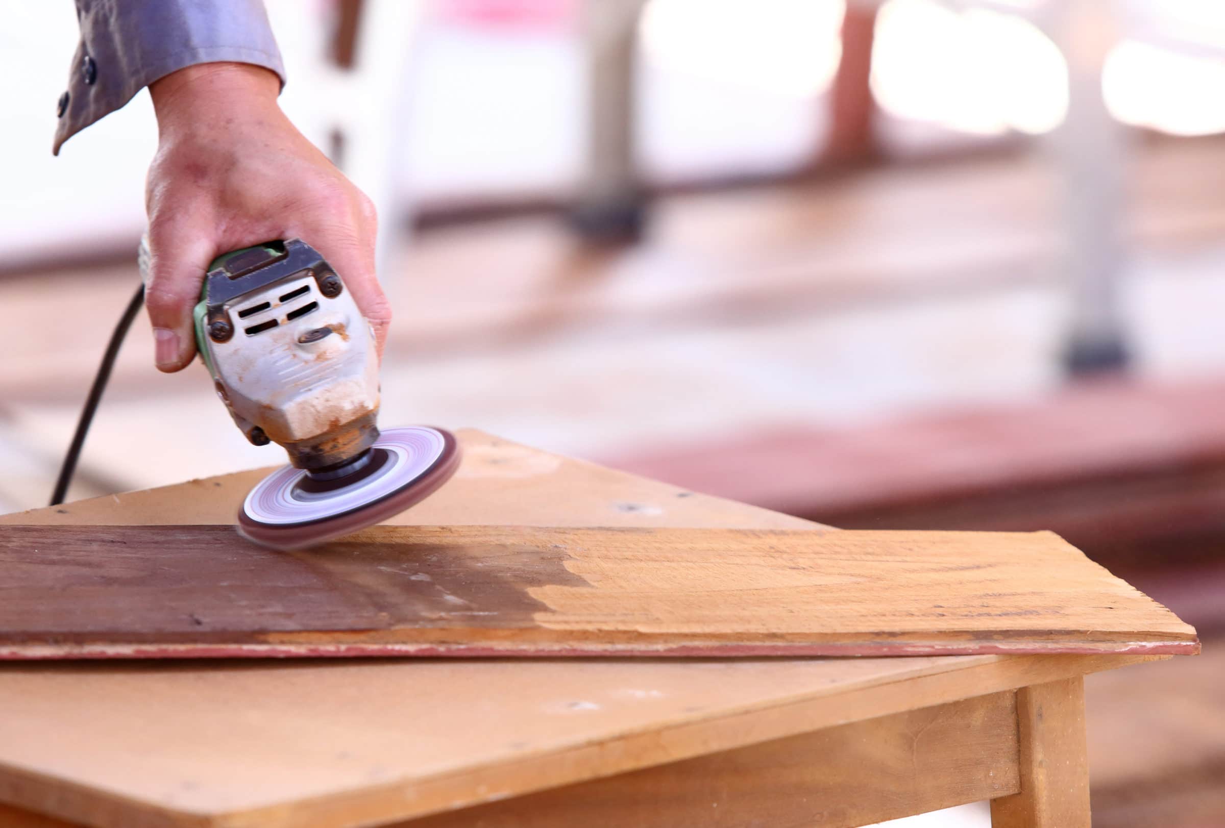 Electric sander being used to remove paint from wood